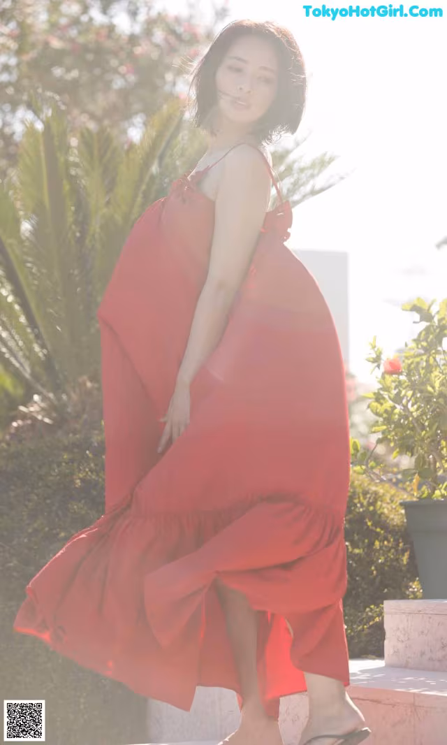 A woman in a red dress is posing for a picture.