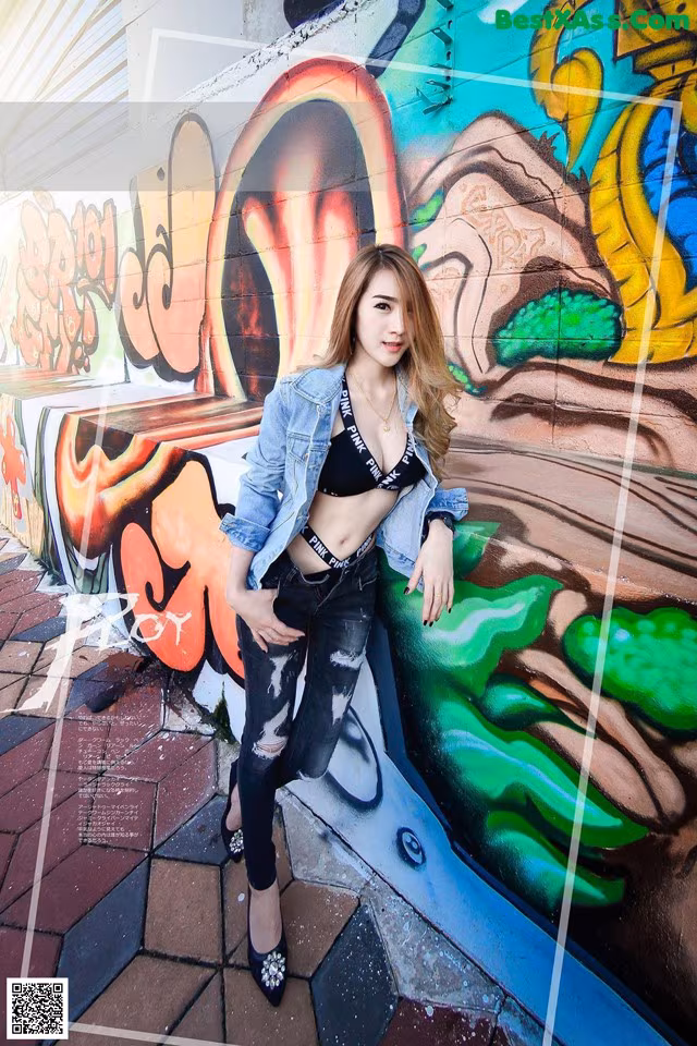 A woman leaning against a wall covered in graffiti.