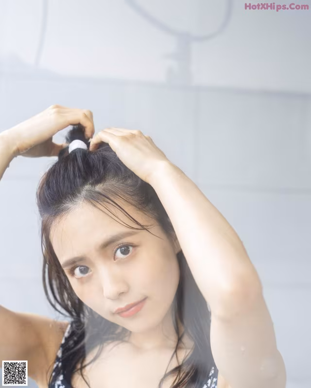 A woman in a black and white bathing suit brushing her hair.