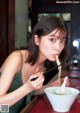A woman eating noodles with chopsticks in a bowl.