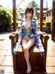 A woman in a blue kimono sitting on a wooden bench.