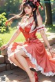 A woman in a red dress sitting on a stone wall.