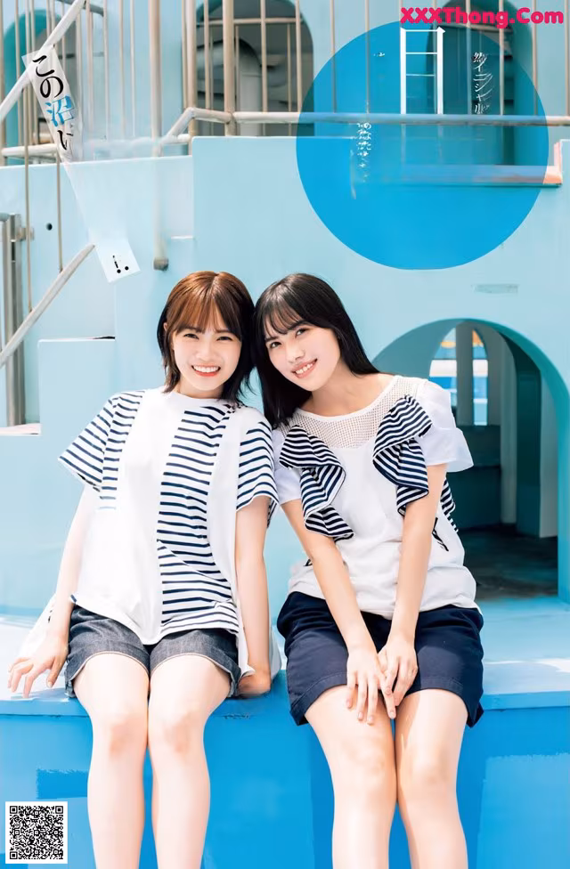 A couple of women sitting next to each other on a blue bench.