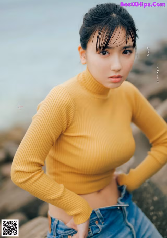 A woman in a yellow sweater and jeans posing for a magazine.