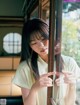 A woman looking out of a window with her hand on the glass.