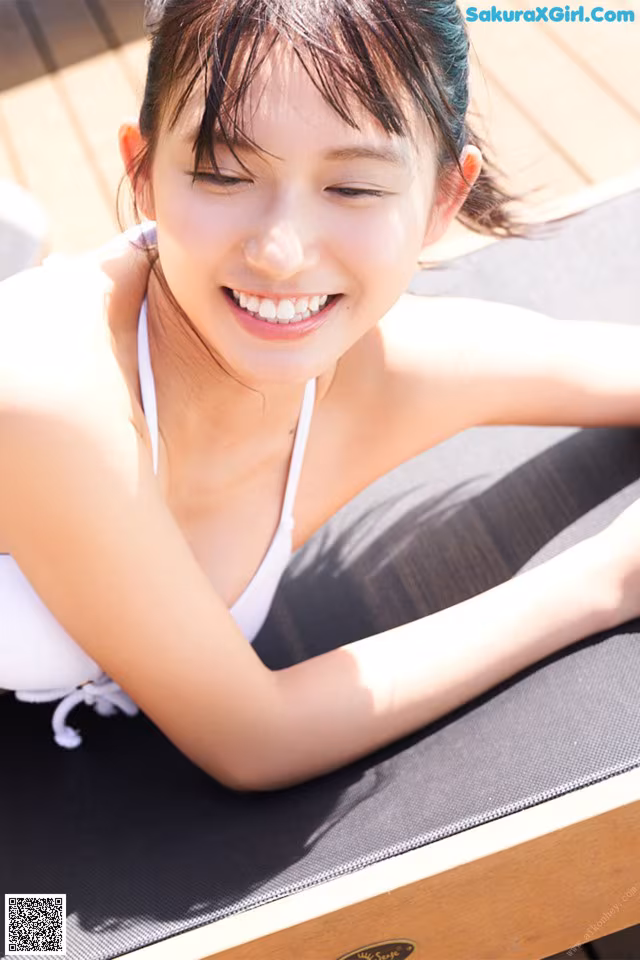 A woman in a white bikini laying on a yoga mat.