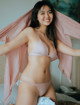 A woman in a pink bikini posing on a bed.