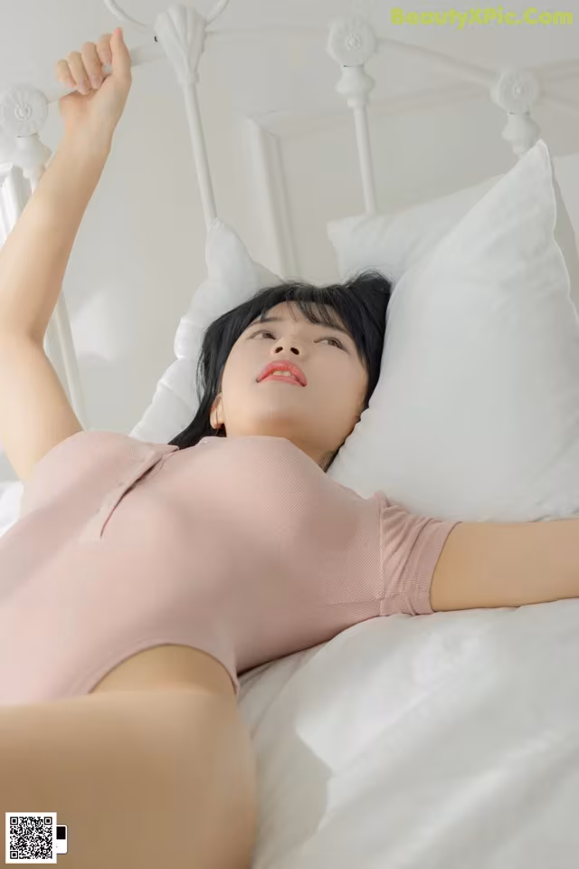 A woman laying on top of a white bed.
