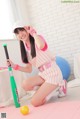 A woman in a pink and white striped outfit holding a baseball bat.