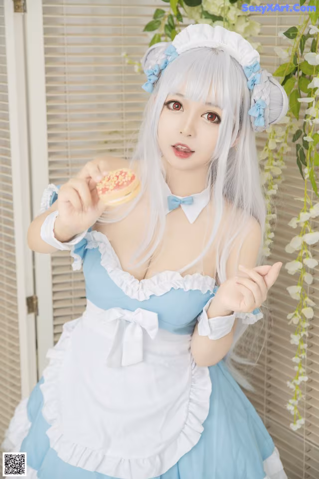 A woman in a blue and white dress holding a donut.
