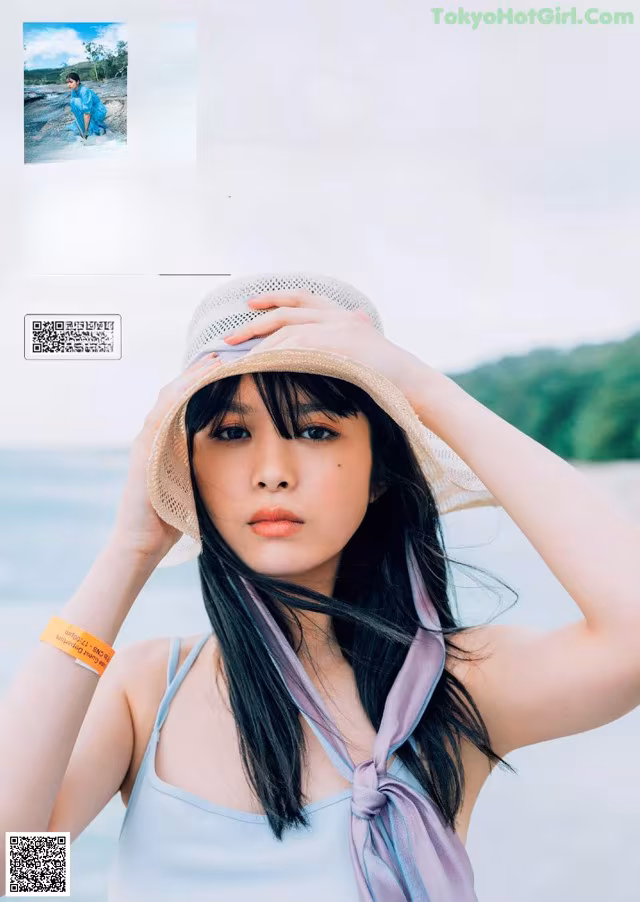 A woman wearing a hat and a scarf on the beach.