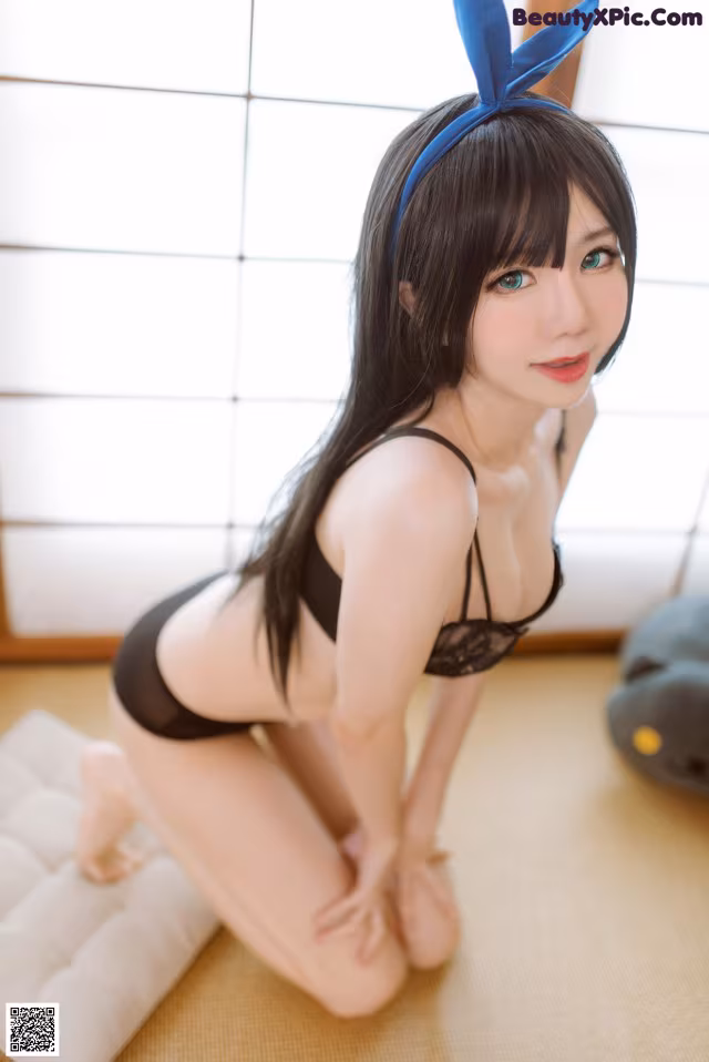 A woman in a black lingerie sitting on the floor.