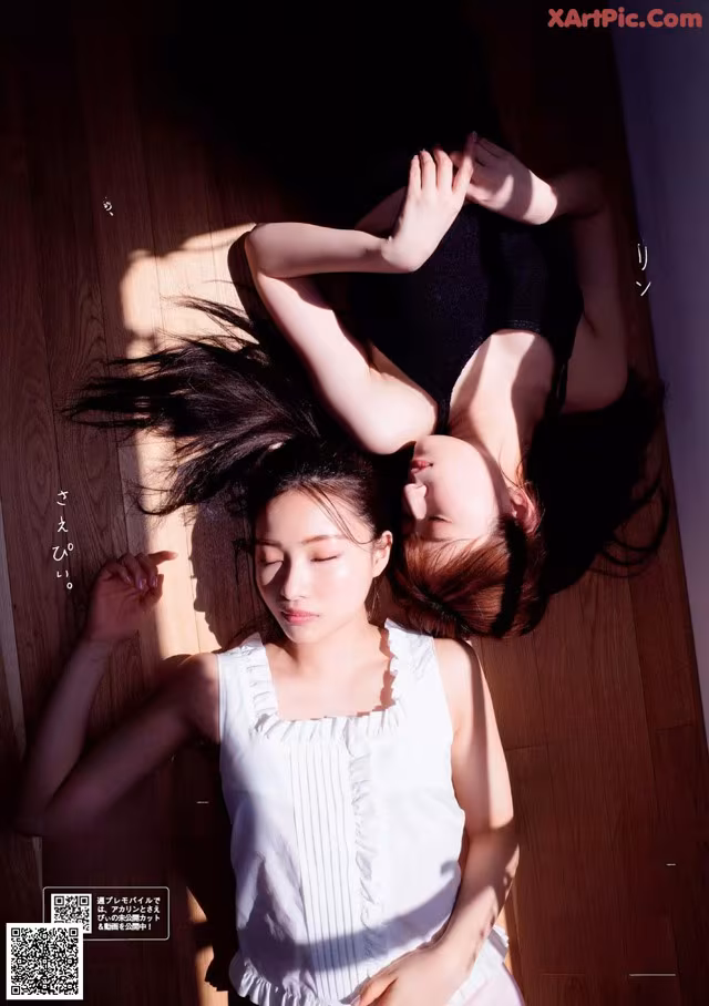 A couple of women laying on top of a wooden floor.
