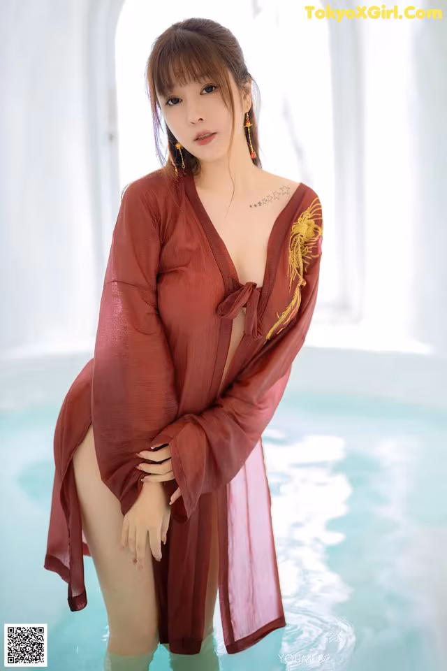 A woman in a red robe standing in a pool.