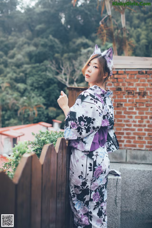 A woman in a kimono standing on a wooden fence.