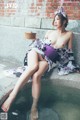 A woman in a kimono sitting on a ledge with a bowl of food.