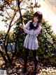 A girl in a school uniform standing next to a tree.