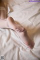 A woman's feet in white stockings on a bed.