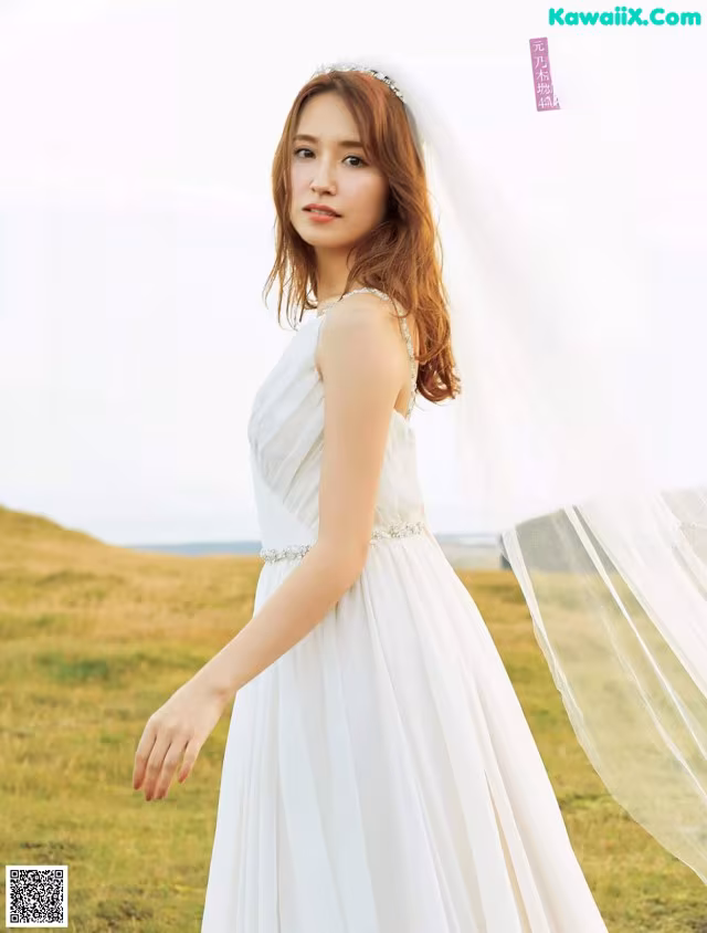 A woman in a white dress standing in a field.