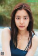 A woman in a blue tank top sitting in a pool.