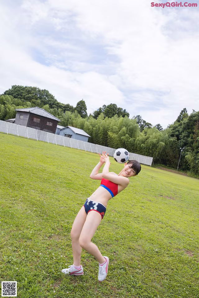 A woman in a bikini playing with a soccer ball.