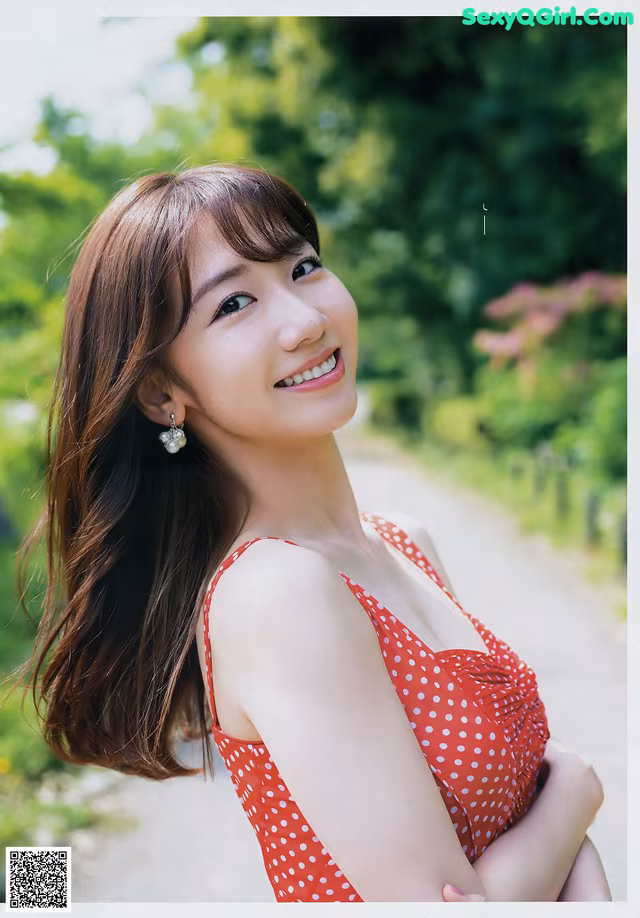 A woman in a red polka dot dress posing for a picture.
