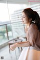 A woman sitting on a window sill looking out a window.